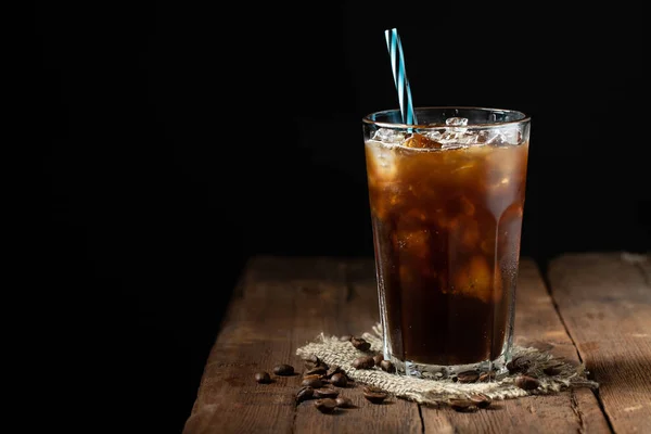 Es kopi dalam gelas tinggi di atas dan biji kopi di atas meja kayu pedesaan tua. Minuman musim panas yang dingin di latar belakang gelap dengan ruang fotokopi — Stok Foto