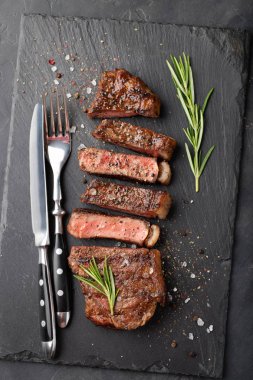 Closeup biftek new York sığır ırkları kara Angus otlar, sarımsak ve bir taş tahta üzerine tereyağı ile yemeye hazır. Bitmiş çanak taş karanlık bir arka plan akşam yemeği için. Üstten Görünüm