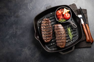 Closeup biftek üst bıçak sığır ırkları siyah yemeye hazır Angus ile ızgara domates, sarımsak ve ahşap bir gemide. Bitmiş çanak taş karanlık bir arka plan akşam yemeği için. Kopya alanı ile üstten görünüm