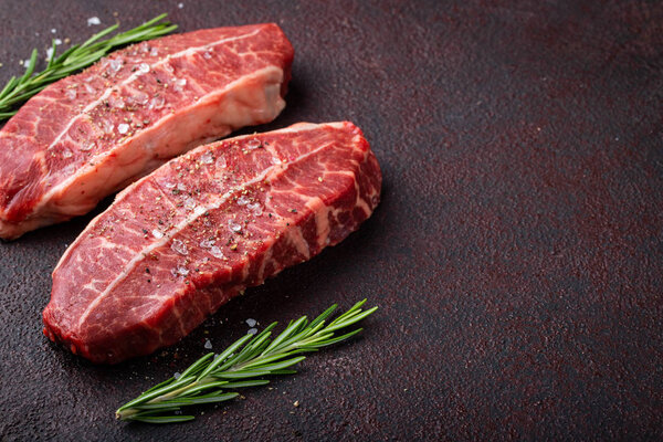 Raw fresh meat Top Blade steaks on dark background. top view with copy space.