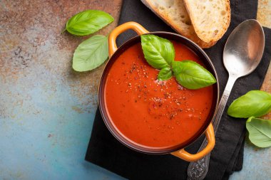 Fesleğen, ekmek ve zeytinyağı taş masanın üzerine ev yapımı domates çorbası. Paslı bir arka plan üzerinde bir vejetaryen tabağı hazırladı. Kopya alanı ile üstten görünüm