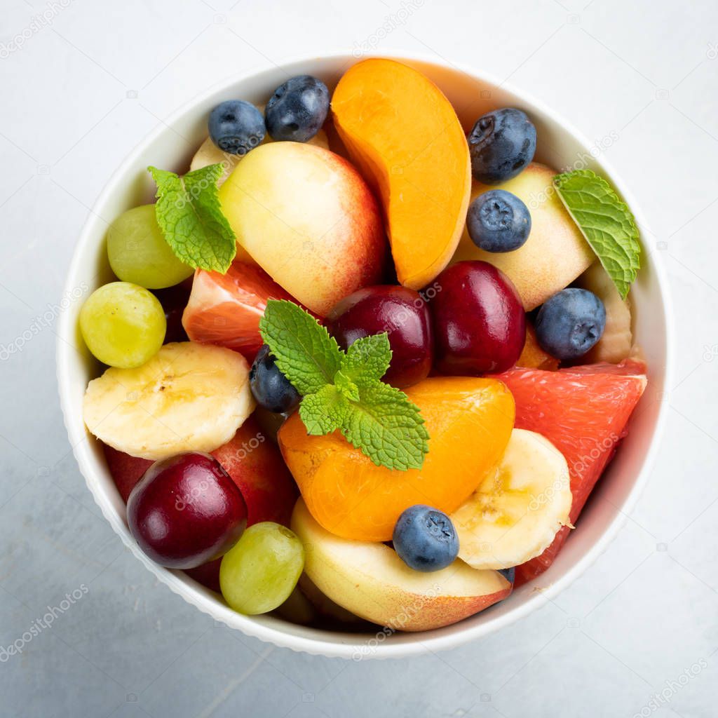Bowl of healthy fresh fruit salad on a white background. Top view.
