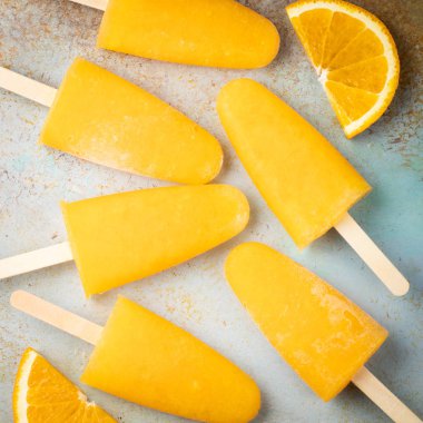 Turuncu çubuklu dondurmayı suyu üzerinde mavi bir arka plan ile. Buz çıkar, düz yatıyordu, en iyi görünümü.