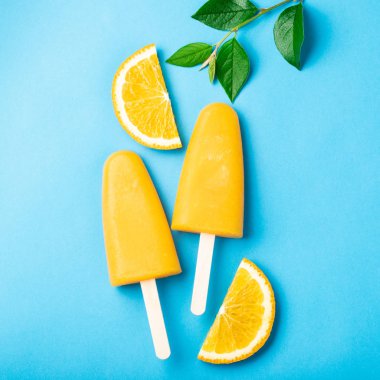 Turuncu çubuklu dondurmayı suyu üzerinde mavi bir arka plan ile. Buz çıkar, düz yatıyordu, en iyi görünümü.