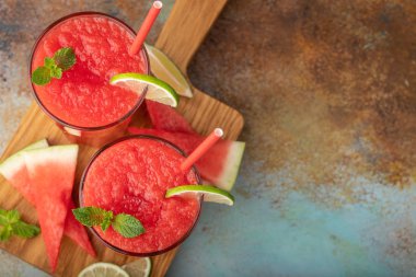 Karpuz meybuz kireç ile yaz ferahlatıcı içeceği paslı mavi bir arka plan üzerinde uzun boylu gözlük olarak. Kopya alanı ile üstten görünüm.