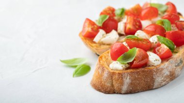 Bruschetta domates, mozzarella peyniri ve fesleğen üzerinde hafif bir arka plan ile. Geleneksel İtalyan meze veya aperatif, meze. Üstten görünüm kopya alanı ile. Düz yatıyordu.