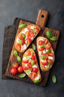 Bruschetta domates, mozzarella peyniri ve fesleğen bir kesme tahtası üzerinde. Geleneksel İtalyan meze veya aperatif, meze. Üstten görünüm. Düz yatıyordu.