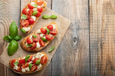 Bruschetta domates, mozzarella peyniri ve fesleğen eski bir rustik tablo. Geleneksel İtalyan meze veya aperatif, meze. Üstten görünüm kopya alanı ile. Düz yatıyordu.
