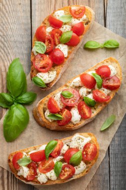 Bruschetta domates, mozzarella peyniri ve fesleğen eski bir rustik tablo. Geleneksel İtalyan meze veya aperatif, meze. Üstten görünüm. Düz yatıyordu.
