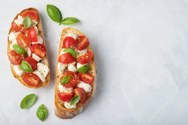 Bruschetta domates, mozzarella peyniri ve fesleğen üzerinde hafif bir arka plan ile. Geleneksel İtalyan meze veya aperatif, meze. Üstten görünüm kopya alanı ile. Düz yatıyordu.