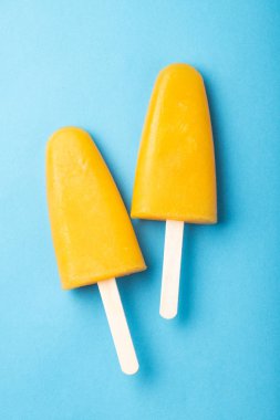 Turuncu çubuklu dondurmayı suyu üzerinde mavi bir arka plan ile. Buz çıkar, düz yatıyordu, en iyi görünümü.
