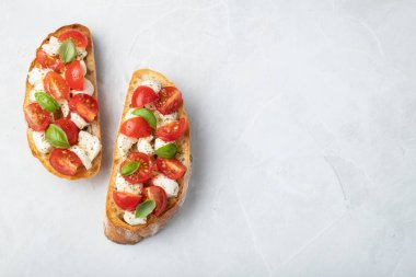Bruschetta domates, mozzarella peyniri ve fesleğen üzerinde hafif bir arka plan ile. Geleneksel İtalyan meze veya aperatif, meze. Üstten görünüm kopya alanı ile. Düz yatıyordu.