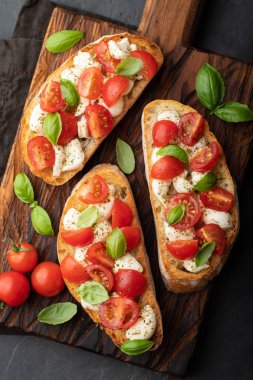 Bruschetta domates, mozzarella peyniri ve fesleğen bir kesme tahtası üzerinde. Geleneksel İtalyan meze veya aperatif, meze. Üstten görünüm. Düz yatıyordu.