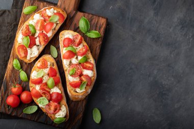 Domates, mozzarella peyniri ve fesleğen dilimleme tahtasında. Geleneksel İtalyan aperatifi veya aperatifi, antipasto. Kopyalama alanı olan üst görünüm. Düz yatıyordu.