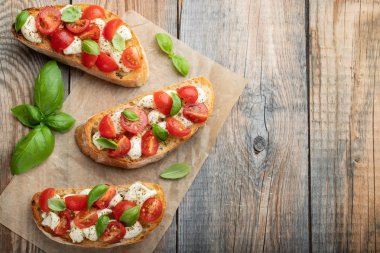 Bruschetta domates, mozzarella peyniri ve fesleğen eski bir rustik tablo. Geleneksel İtalyan meze veya aperatif, meze. Üstten görünüm kopya alanı ile. Düz yatıyordu.