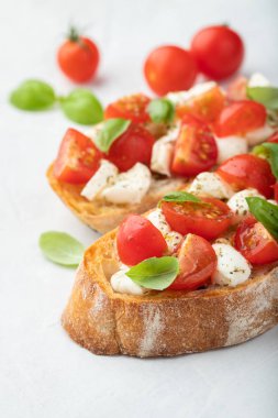 Bruschetta domates, mozzarella peyniri ve fesleğen üzerinde hafif bir arka plan ile. Geleneksel İtalyan meze veya aperatif, meze