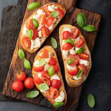 Bruschetta domates, mozzarella peyniri ve fesleğen bir kesme tahtası üzerinde. Geleneksel İtalyan meze veya aperatif, meze. Üstten görünüm. Düz yatıyordu