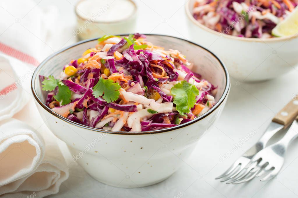 Purple cabbage and carrot salad with mayonnaise in a white bowl on a light background. Classic coleslaw. Diet vegetarian dish.