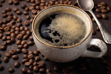 Bir fincan sade kahve ve kahve çekirdekleri karanlık bir arka plan üzerinde Close-up.