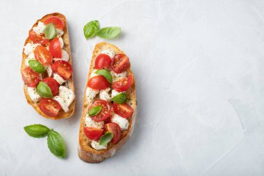 Bruschetta domates, mozzarella peyniri ve fesleğen üzerinde hafif bir arka plan ile. Geleneksel İtalyan meze veya aperatif, meze. Üstten görünüm kopya alanı ile. Düz yatıyordu.