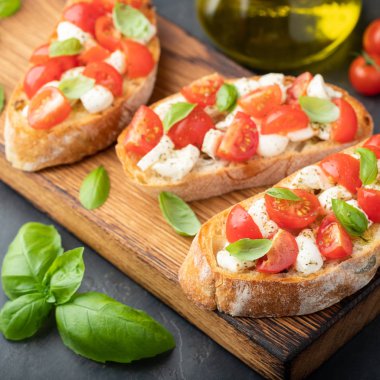 Domates, mozzarella peyniri ve fesleğen dilimleme tahtasında. Geleneksel İtalyan aperatifi veya aperatifi, antipasto.