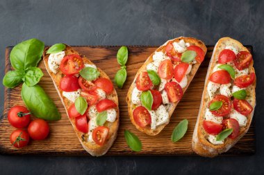 Domates, mozzarella peyniri ve fesleğen dilimleme tahtasında. Geleneksel İtalyan aperatifi veya aperatifi, antipasto. Kopyalama alanı olan üst görünüm. Düz yatıyordu.