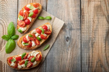 Bruschetta domates, mozzarella peyniri ve fesleğen eski bir rustik tablo. Geleneksel İtalyan meze veya aperatif, meze. Üstten görünüm kopya alanı ile. Düz yatıyordu.