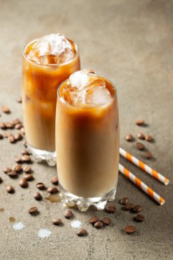 Krem üzerine dökülür ve kahve çekirdekleri ile uzun bir bardak buzlu kahve. Soğuk yaz içeceği kahverengi paslı arka plan üzerinde.