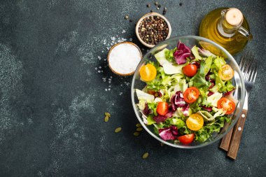 Sağlıklı sebze salatası, taze domates, salatalık, soğan, ıspanak, marul ve kase kabak çekirdeği. Diyet menüsü. Kopya alanı ile üstten görünüm.