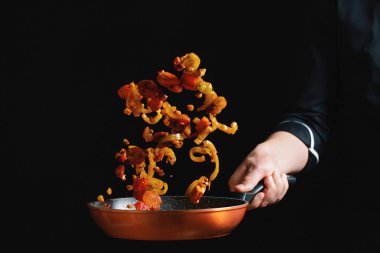 Bir tavada sebze yemek Şef. Siyah arka plan kopya alanı metni ile. Hareketleri dondur.