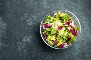 Sağlıklı sebze salatası, taze domates, salatalık, soğan, ıspanak, marul ve kase kabak çekirdeği. Diyet menüsü. Kopya alanı ile üstten görünüm.