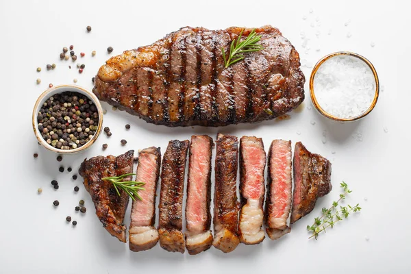 İki ızgara mermer sığır eti biftek striploin beyaz arka plan üzerinde üstten görünüm izole baharatlar ile.