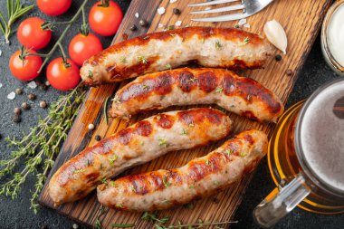 Soslar ve otlar üzerinde ahşap hizmet yönetim kurulu ile kızarmış sosis. Karanlık bir arka plan üzerinde büyük bira Aperatif. Üstten görünüm.