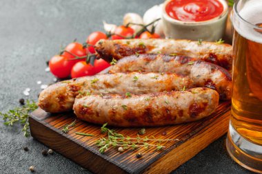 Soslar ve otlar üzerinde ahşap hizmet yönetim kurulu ile kızarmış sosis. Karanlık bir arka plan üzerinde büyük bira Aperatif. Kopya alanı ile.