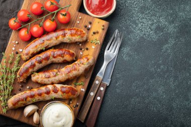 Soslar ve otlar üzerinde ahşap hizmet yönetim kurulu ile kızarmış sosis. Karanlık bir arka plan üzerinde büyük bira Aperatif. Kopya alanı ile üstten görünüm.