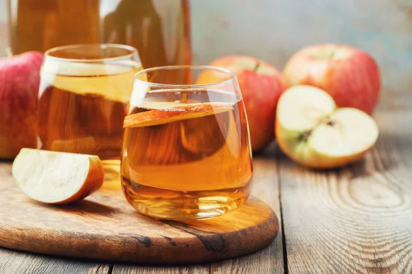 Sari apel organik atau jus di atas meja kayu. Dua gelas dengan minuman dan daun musim gugur dengan latar belakang pedesaan — Stok Foto