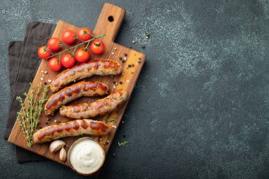 Soslar ve otlar üzerinde ahşap hizmet yönetim kurulu ile kızarmış sosis. Karanlık bir arka plan üzerinde büyük bira Aperatif. Kopya alanı ile üstten görünüm.