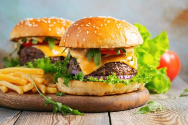 İki taze ev yapımı Hamburger ahşap bir masa üzerinde kızarmış patates ile.