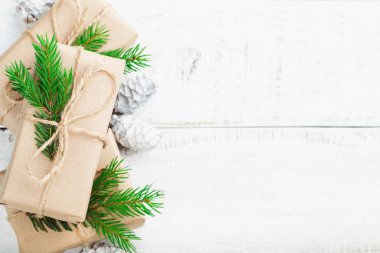 Noel kompozisyonu. Noel hediyesi, çam kozalakları, tahta beyaz arka planda köknar dalları. Düz konum, üst görünüm, kopyalama alanı.