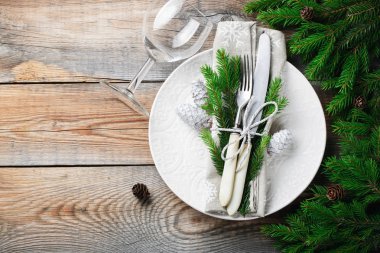 Noel süslemeleri ile Noel tablo ayarı. Beyaz tabak, çatal bıçak takımı, çam kozalakları ve havlu ile eski rustik ahşap arka plan üzerinde kar taneleri. Mutlu yeni yıl 2019. Görünümü en çok, uzay kopyalayın. Düz yatıyordu