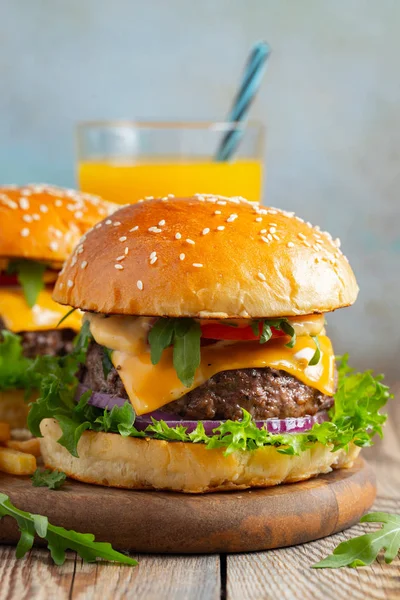Dos hamburguesas caseras frescas con papas fritas y jugo de naranja en una mesa de madera — Foto de Stock