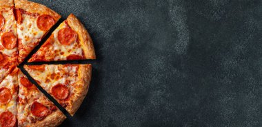 Lezzetli biberli pizza ve siyah beton arka planda domates fesleğeni. Acı biberli pizzanın en iyi manzarası. Metin için kopyalama alanı ile. Düz yatıyordu. Pankart.