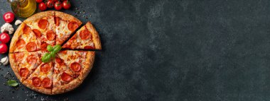 Lezzetli biberli pizza ve siyah beton arka planda domates fesleğeni. Acı biberli pizzanın en iyi manzarası. Metin için kopyalama alanı ile. Düz yatıyordu. Pankart.