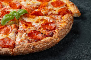 Lezzetli biberli pizza ve pişirme malzemeleri domates fesleğen siyah arka plan beton.
