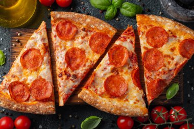 Lezzetli biberli pizza ve pişirme malzemeleri domates fesleğen siyah arka plan beton. Üstten görünüm sıcak biberli pizza. Düz yatıyordu