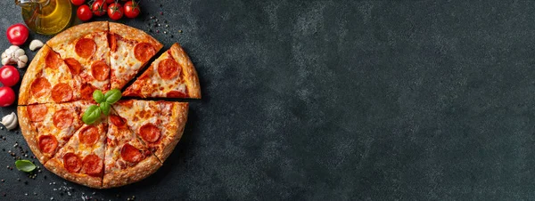 Lezzetli biberli pizza ve siyah beton arka planda domates fesleğeni. Acı biberli pizzanın en iyi manzarası. Metin için kopyalama alanı ile. Düz yatıyordu. Pankart.