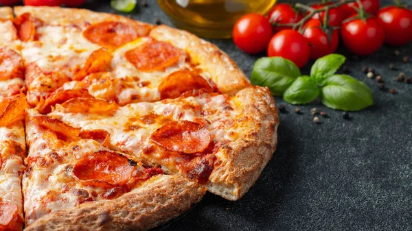 Leckere Pfefferoni-Pizza und Kochzutaten Tomaten Basilikum auf schwarzem Betonhintergrund — Stockfoto
