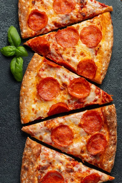 Gustosi peperoni pizza e ingredienti di cottura pomodori basilico su sfondo nero cemento. Vista dall'alto della pizza piccante al peperoncino. Posa piatta — Foto Stock