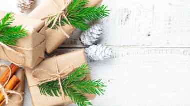 Noel kompozisyonu. Noel hediyesi, çam kozalakları, tahta beyaz arka planda köknar dalları. Düz konum, üst görünüm, kopyalama alanı.