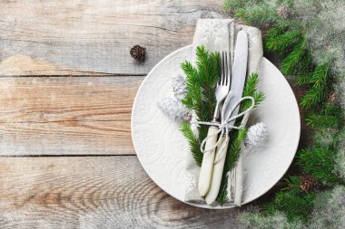 Noel süslemeleri ile Noel tablo ayarı. Beyaz tabak, çatal bıçak takımı, çam kozalakları ve havlu ile eski rustik ahşap arka plan üzerinde kar taneleri. Mutlu yeni yıl 2019. Görünümü en çok, uzay kopyalayın. Düz yatıyordu.